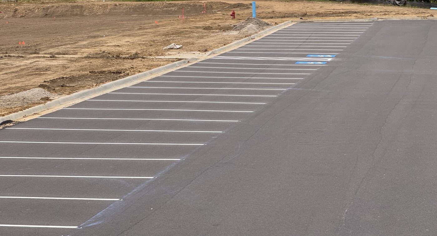 Fresh white parking stripes with ADA access aisle hatching and accessible parking symbols on a new commercial lot